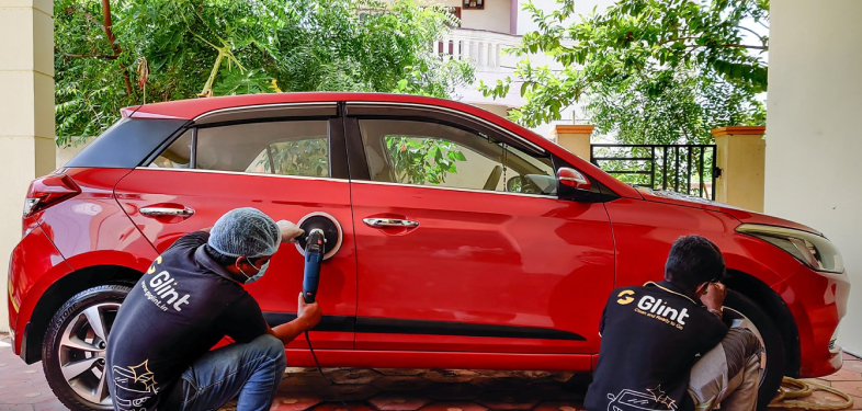 Glint Car Care Partners Detailing a car exterior.